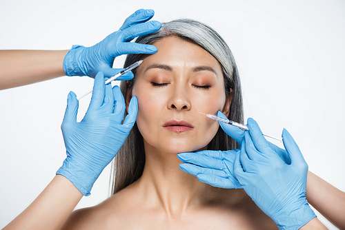 nude asian woman and doctors in latex gloves holding syringes with beauty injections isolated on grey