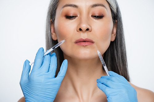beautiful nude asian woman and doctors in latex gloves holding syringes with beauty injections isolated on grey