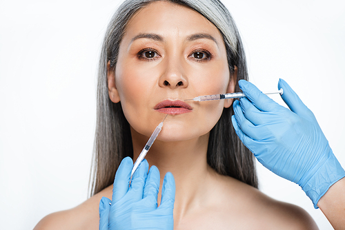 naked asian woman and doctors in latex gloves holding syringes with beauty injections isolated on grey