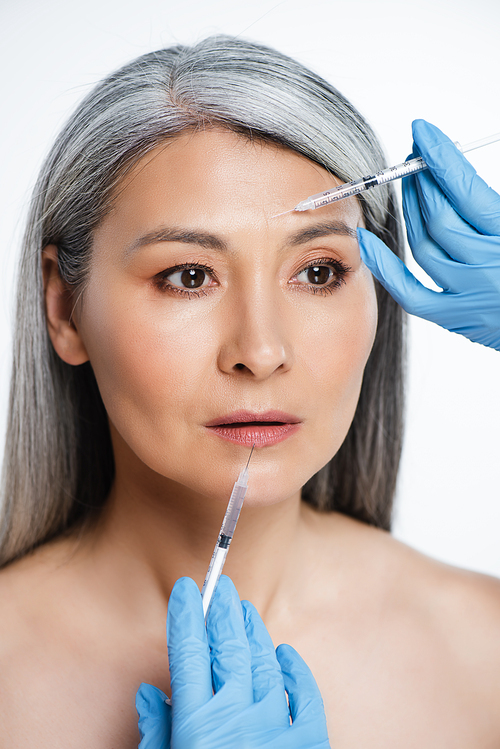 attractive naked asian woman and doctors in latex gloves holding syringes with beauty injections isolated on grey