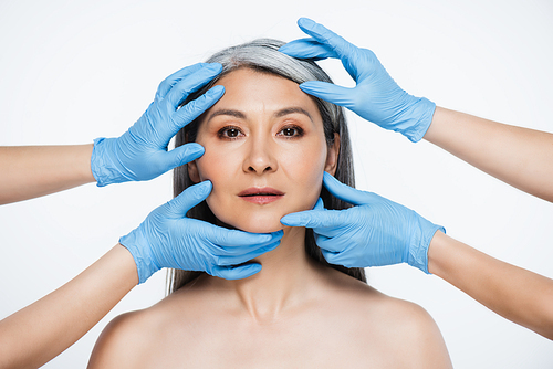 doctors in latex gloves touching face of naked asian woman isolated on grey