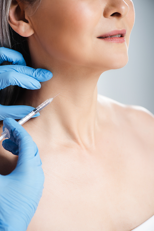 cropped view of smiling naked woman and doctor in latex gloves holding syringe with beauty injection isolated on grey