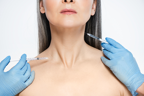 cropped view of nude asian woman and doctors in latex gloves holding syringes with beauty injections isolated on grey