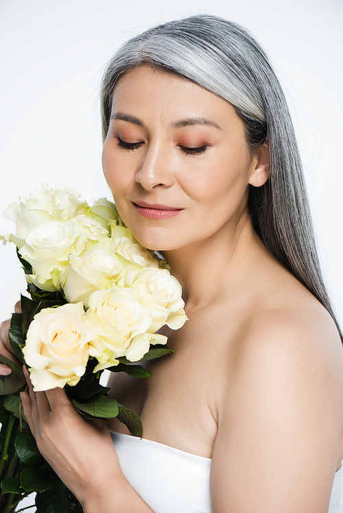 attractive tender naked asian woman with grey hair holding bouquet of white roses isolated on grey