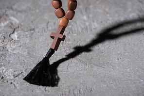 wooden rosary with cross on grey textured surface