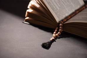 holy bible with rosary on black dark background with sunlight