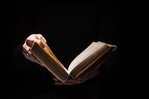 cropped view of woman holding holy bible isolated on black