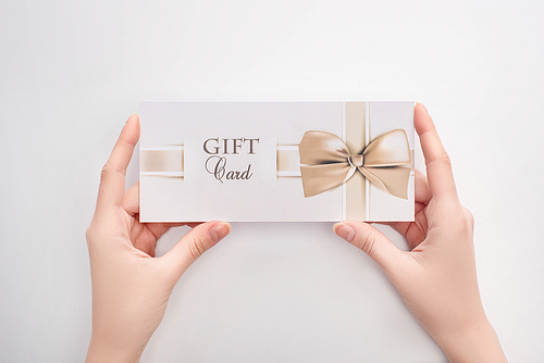Top view of woman holding gift card in hands on white background