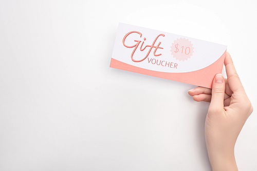Top view of woman holding gift voucher with 10 dollars sign on white surface