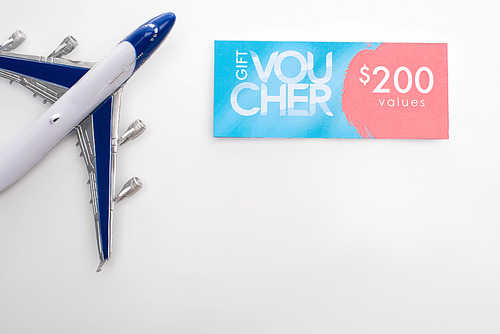 Top view of toy plane near gift voucher with 200 values sign on white background