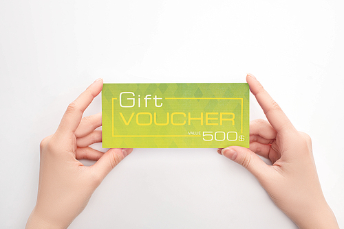 Cropped view of woman holding green gift voucher with value lettering on white background