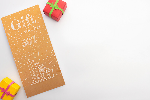 Top view of gift voucher with 50 percents sign and presents on white background