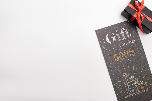 Top view of gift voucher near black present on white background