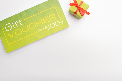 Top view of gift voucher and present on white background with copy space