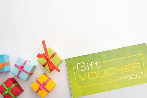 Top view of gift boxes near green gift voucher on white background