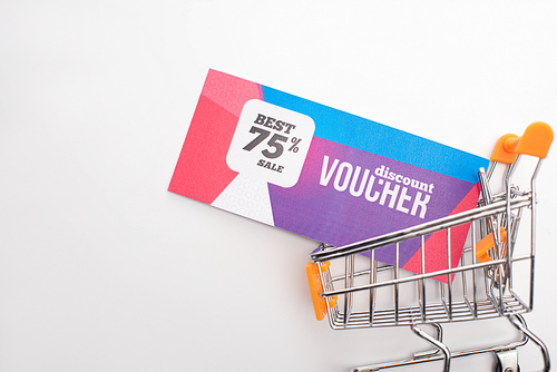 Top view of discount voucher in toy shopping cart on white background