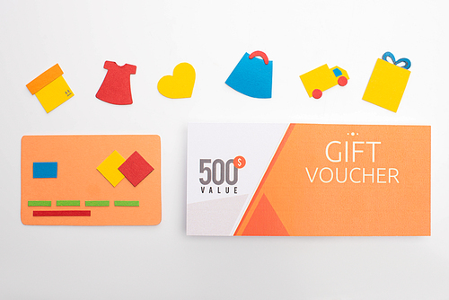 Top view of paper credit card near gift voucher and paper craft on white background