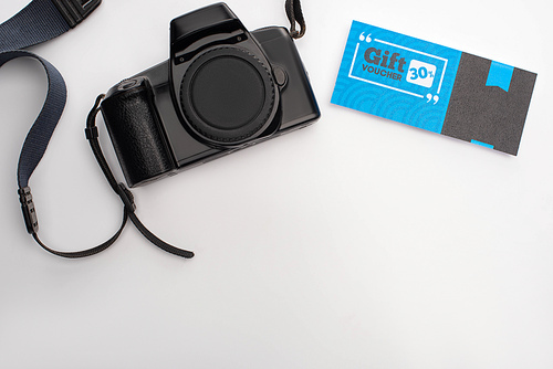 Top view of digital camera and gift voucher with 30 percents on white background