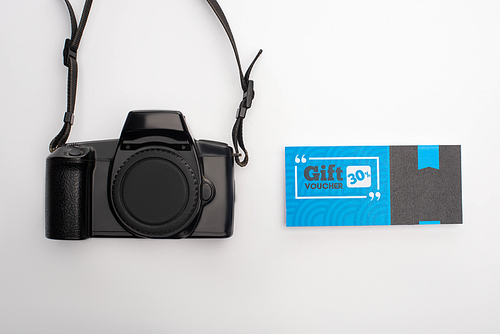 Top view of digital camera and gift voucher with percent sign on white background