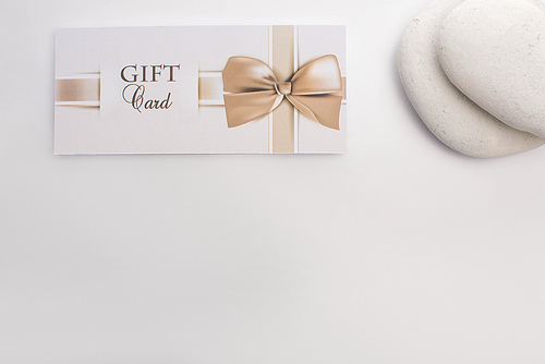 Top view of gift card near zen stones on white background
