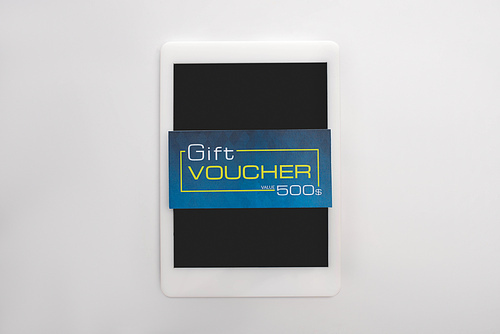 Top view of gift voucher on digital tablet on white background