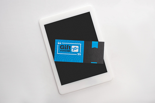 Top view of gift voucher with 30 percents sign on digital tablet on white surface