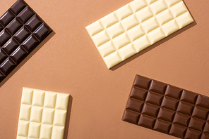 top view of delicious whole milk, white and dark chocolate bars on dark background