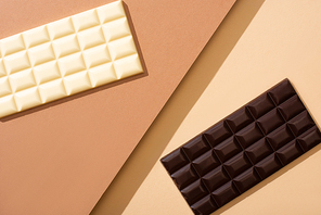 top view of delicious whole white and dark chocolate bars on beige background