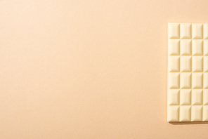 top view of delicious white chocolate bar on beige background