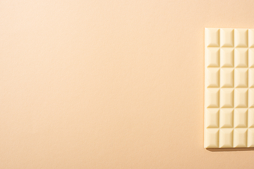 top view of delicious white chocolate bar on beige background