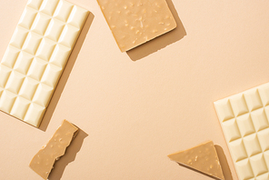 top view of delicious broken and whole white chocolate bars on beige background