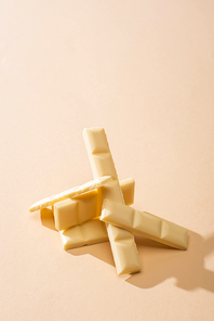 sweet delicious broken white chocolate bar on beige background