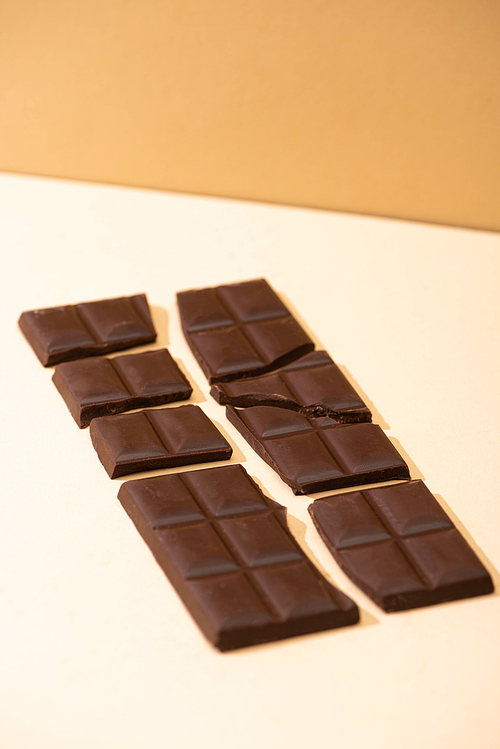 sweet delicious broken dark chocolate on beige background