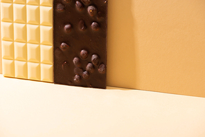 delicious broken white and dark chocolate bars with nuts on beige background