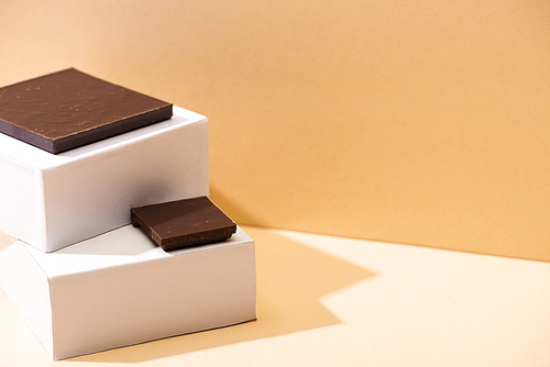 delicious dark chocolate pieces and square cubes on beige background