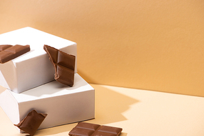 delicious milk chocolate pieces and square cubes on beige background