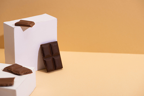 delicious dark and milk chocolate pieces and square cubes on beige background