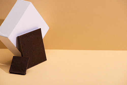 delicious dark chocolate pieces and cube on beige background