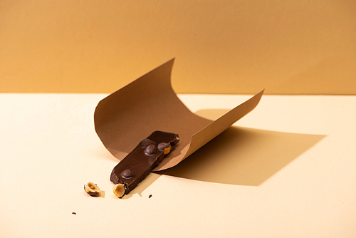 delicious dark chocolate with nuts piece and paper on beige background
