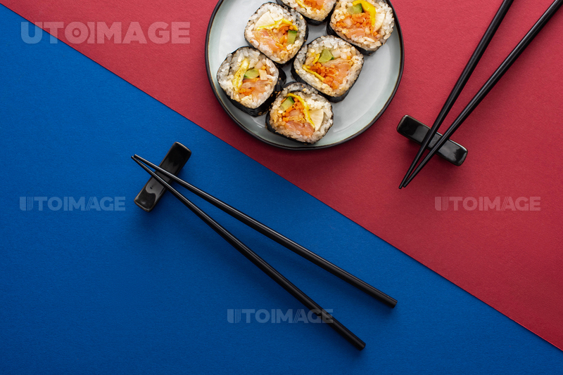유토이미지 top view of chopsticks near plate with delicious gimbap on crimson and blue