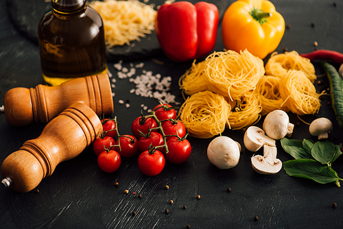 raw Italian Capellini with vegetables on black background