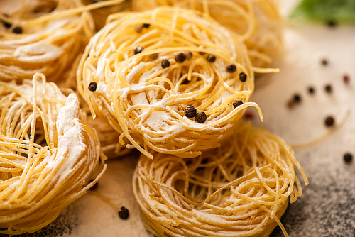 close up view of raw Italian Capellini with flour and black pepper