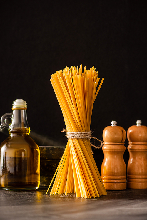 uncooked Italian spaghetti with olive oil and condiments isolated on black