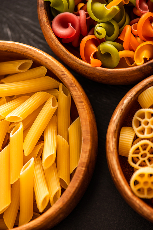 close up view of various raw Italian pasta in wooden bowls