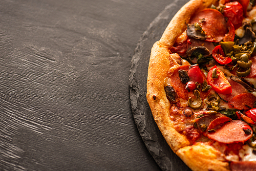 top view of delicious italian pizza with s and salami on black wooden background