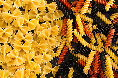 top view of raw colorful fusilli and farfalle pasta