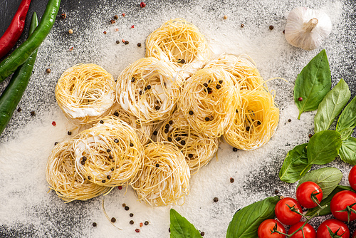 top view of raw Capellini pasta with vegetables, spices and flour