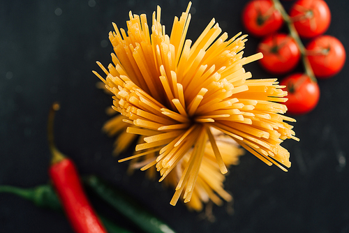 selective focus of raw Italian spaghetti and vegetables isolated on black