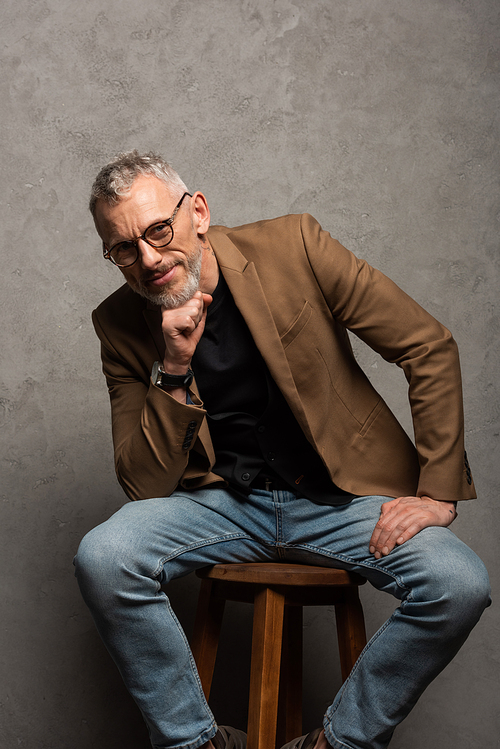 happy businessman in glasses  while sitting on grey
