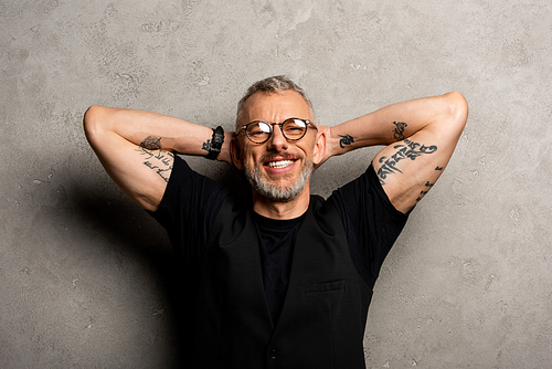 happy and tattooed man in glasses  on grey